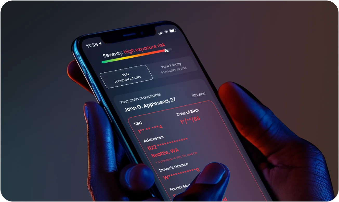 Hand holding a smartphone displaying a data breach alert app showing high exposure risk and personal information details.