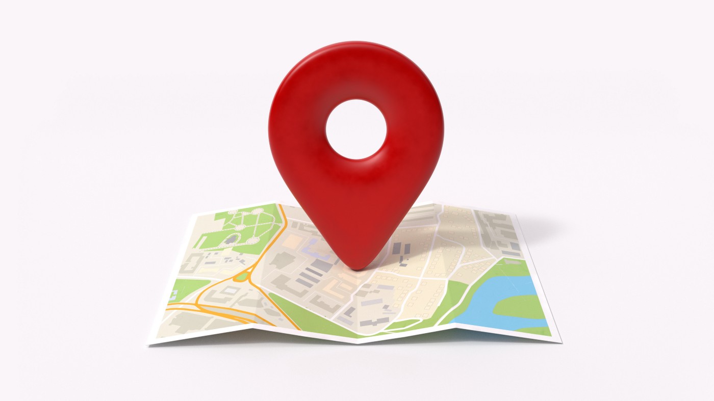 Paper map open with a large red location symbol on top of it