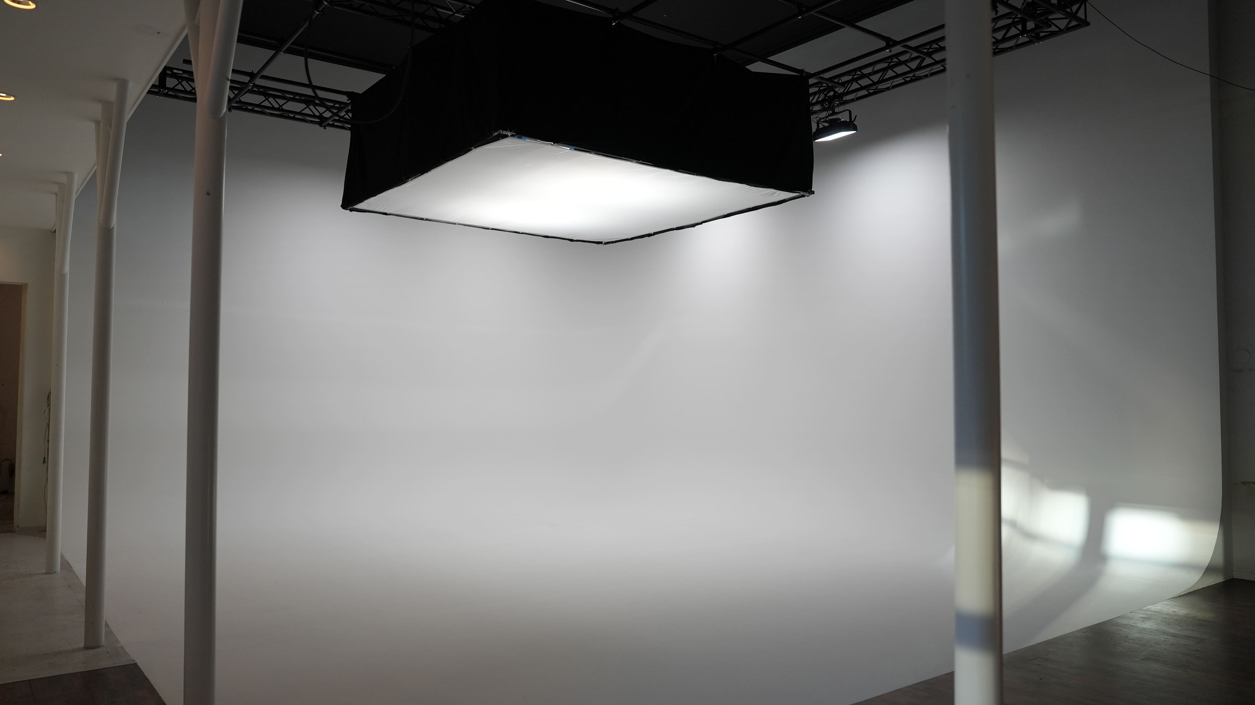 Tomt fotostudieområde med hvidt baggrundsstof og loftbelysning.