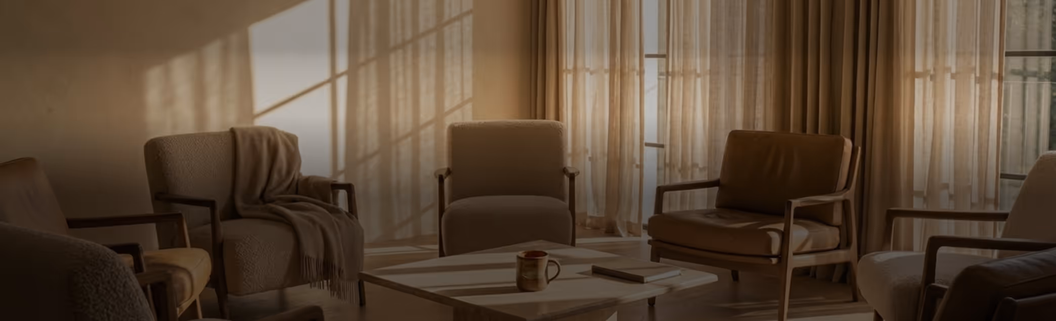 Cozy group therapy room with six armchairs arranged in a circle and a coffee table with a mug and book in the center.