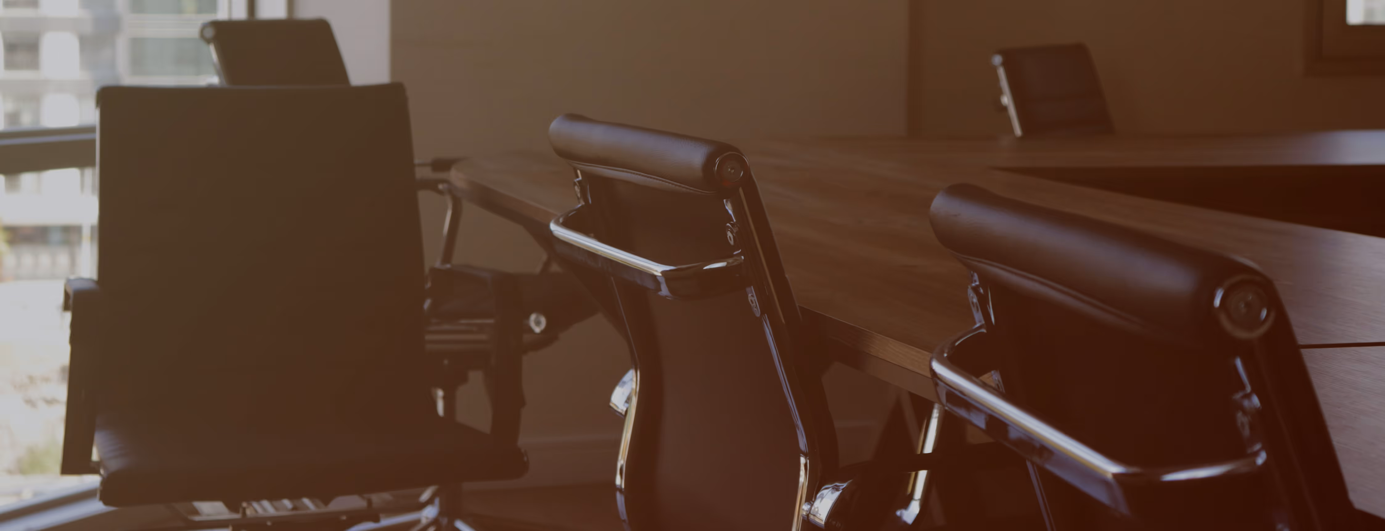 Empty modern office conference room with black leather chairs and a wooden table.