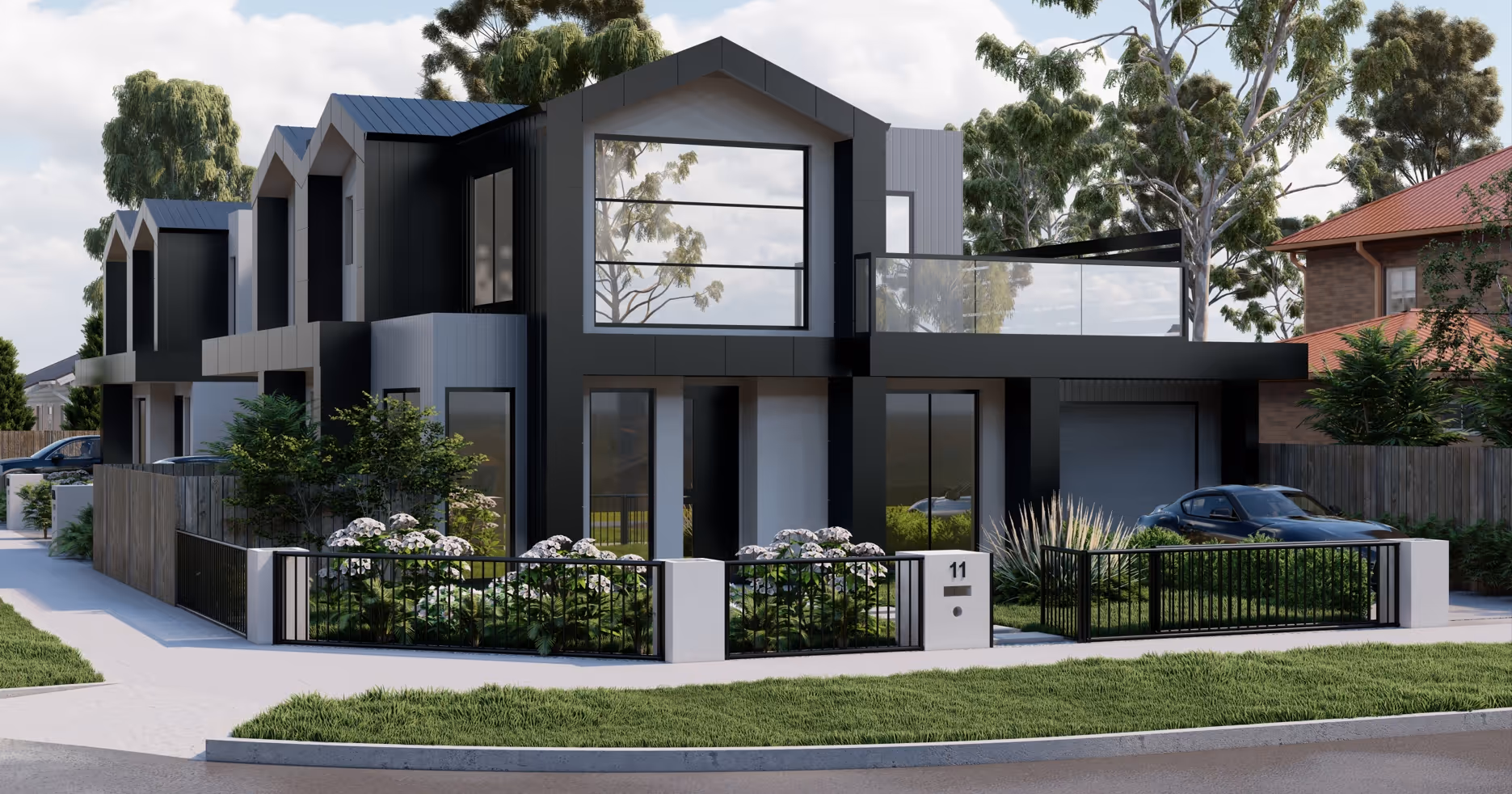 Modern two-story townhouse with black and gray exterior, large windows, front garden with white flowers, and a driveway with a parked car.