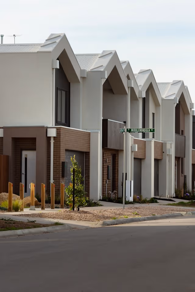 Row of modern townhouses with peaked roofs along a quiet street in Australia