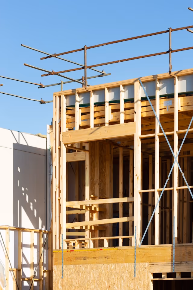 Wooden frame structure of a building under construction with clear blue sky in the background.