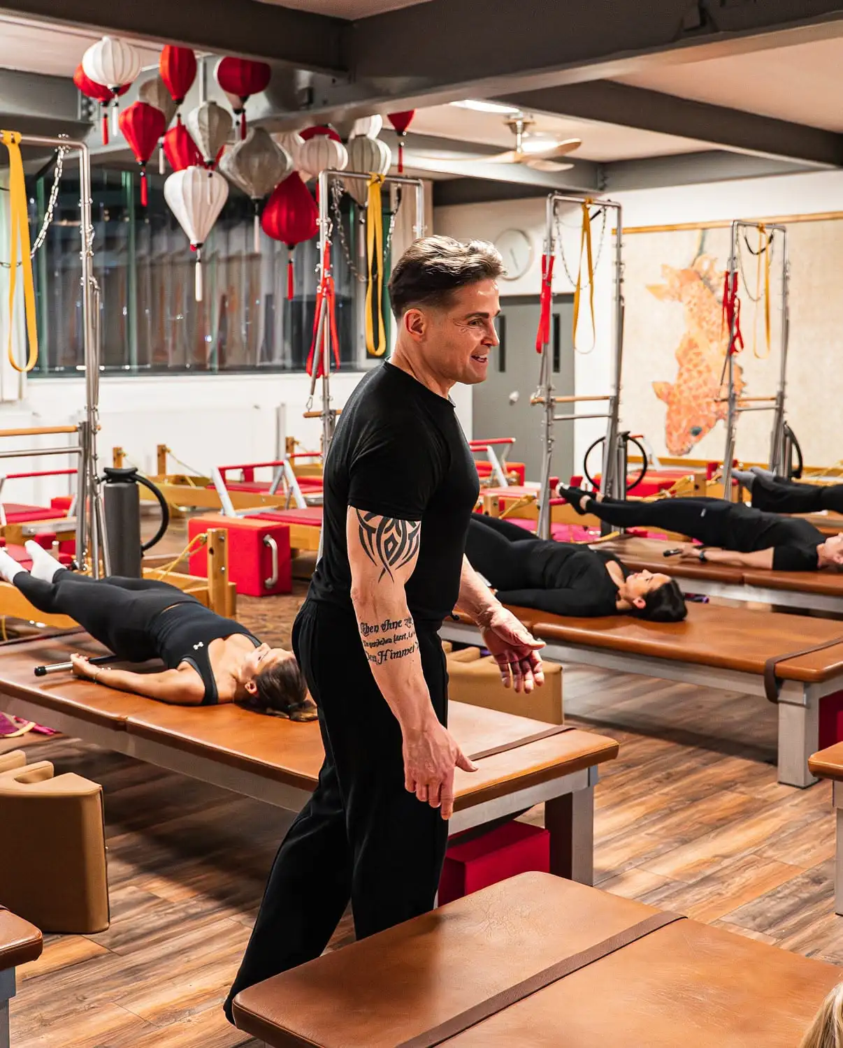 Pilates-Trainer überwacht Teilnehmer beim Training auf Wall Unit (Matte) in einem Pilates Studio Hannover
