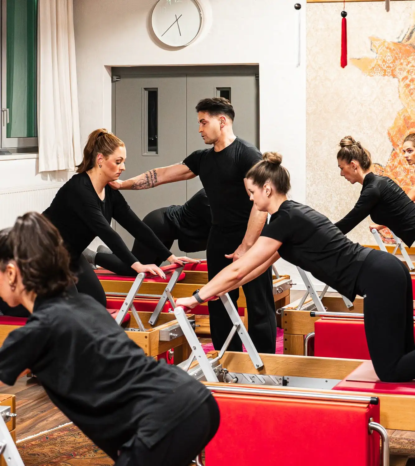 Pilates-Lehrer korrigiert Haltung einer Frau auf einem Reformer-Gerät im Pilates-Studio Hannover