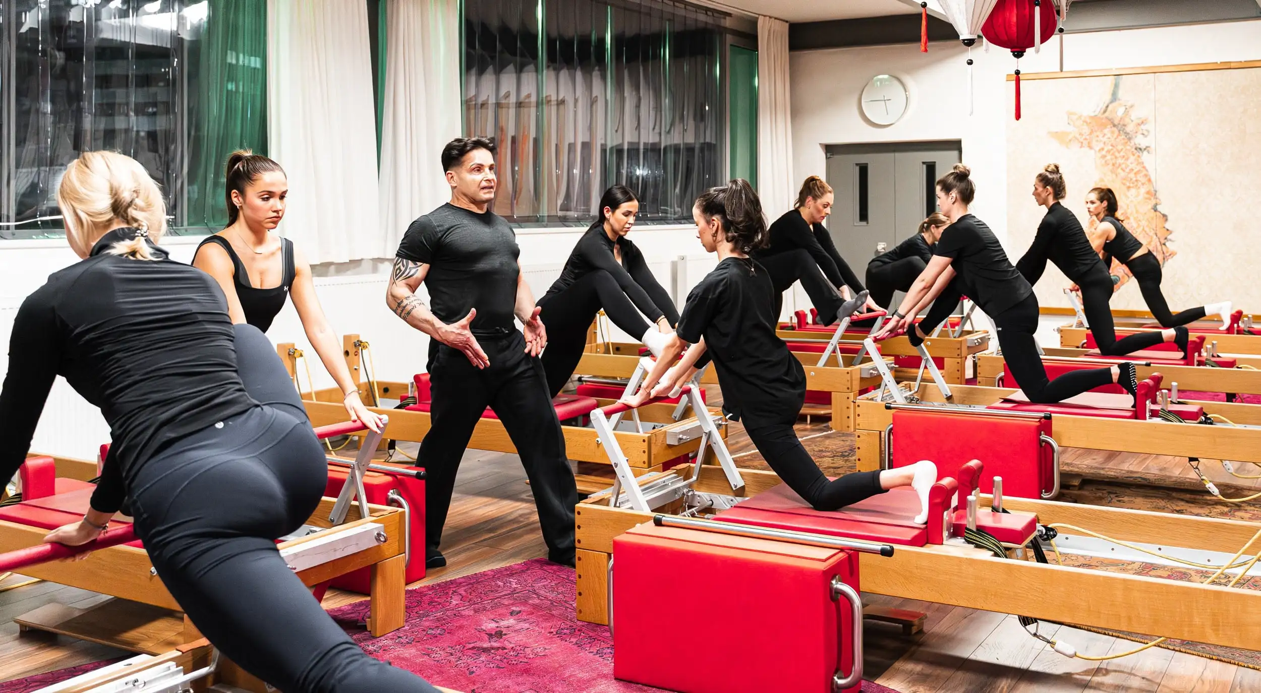 Mehrere Personen in einem Pilates-Studio in Hannover trainieren auf Reformer-Geräten unter Anleitung eines Pilates Trainers.