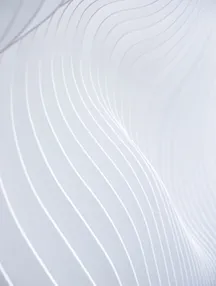 Close-up of smooth white surface with curved, parallel linear grooves creating a flowing pattern.