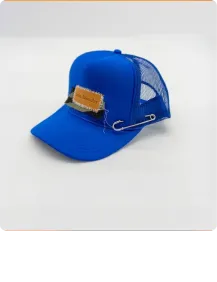 Blue mesh baseball hat with a brown leather patch and a large safety pin attached.