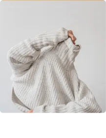 Person wearing a light gray ribbed knit sweater with long sleeves and a high collar.