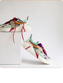Pair of colorful modern sneakers with red laces displayed on white platform against a light background.