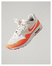 White and orange Nike Air Max sneaker with visible air sole against a plain light background.