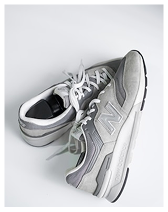 Pair of gray New Balance sneakers with white laces on a white background.