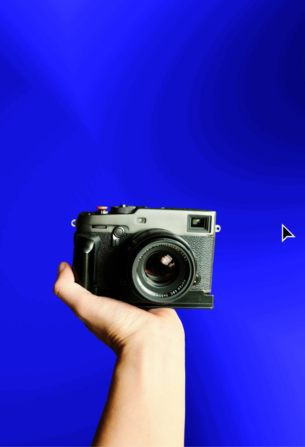 Hand holding a black vintage-style camera against a solid bright blue background.