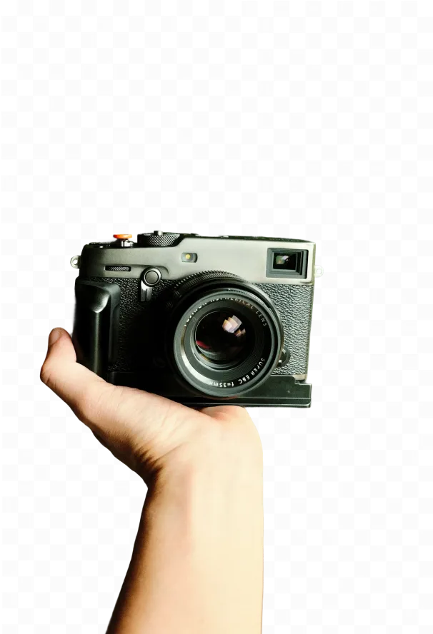 Hand holding a black digital camera facing forward with visible lens and controls.