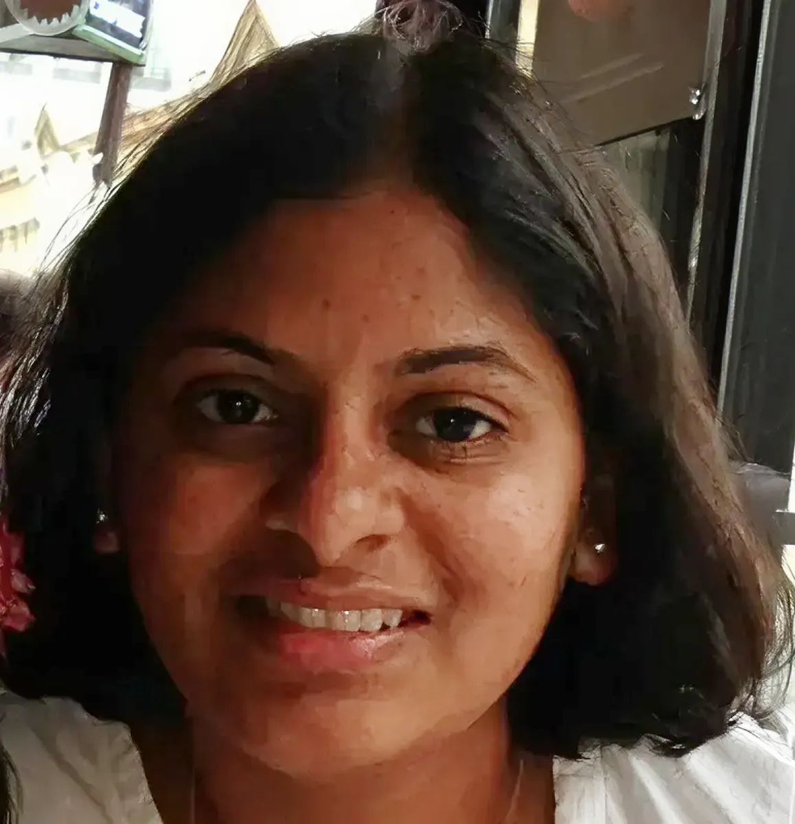 Close-up of a smiling woman with medium-length dark hair wearing a white top.