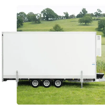 White cargo trailer with triple axles parked on green grass with trees and hills in the background.