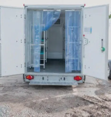 Open rear doors of a refrigerated truck showing plastic strip curtains and empty interior.
