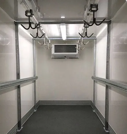 Interior of a refrigerated truck with overhead hooks and side rails for hanging meat.