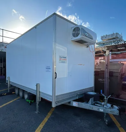 White refrigerated trailer parked outdoors with cooling unit mounted on front.