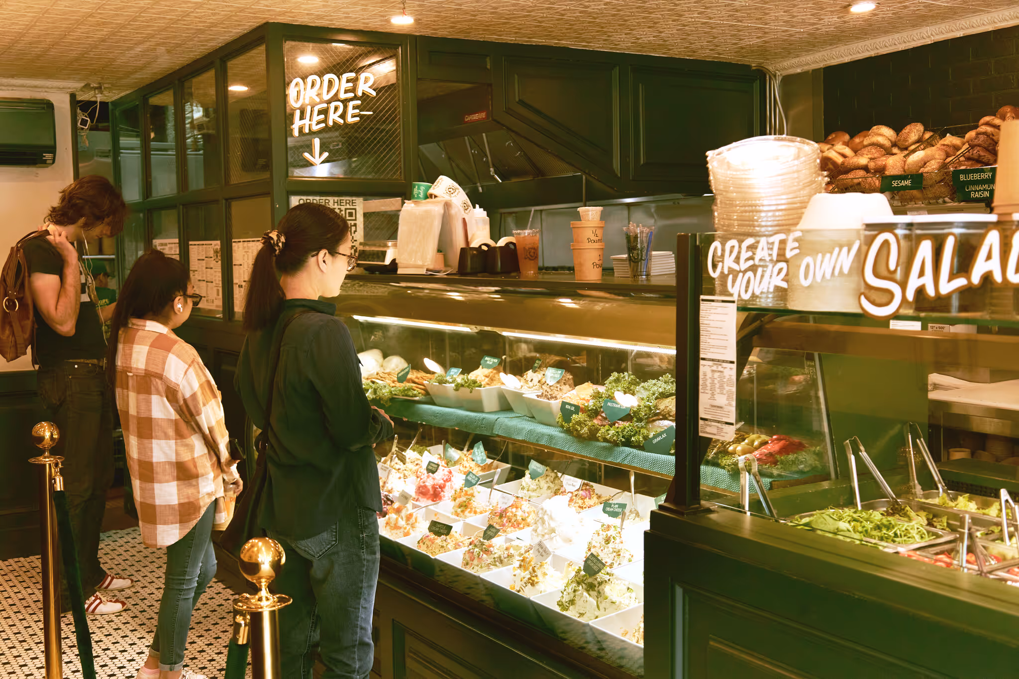 a photo of several customers waiting behind the emerald green and woody counter of the Bagel Pub at Sunset Park