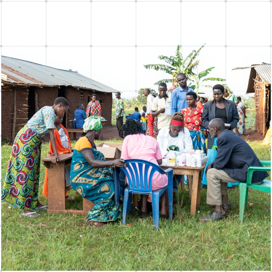 Healthcare workers at an outdoor medical clinic providing consultations and medication to villagers in a rural community.