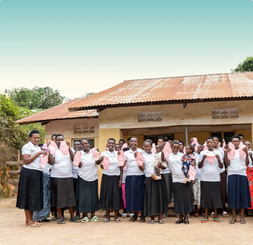 Smiling person holding fresh green leafy vegetables standing outdoors in a garden.