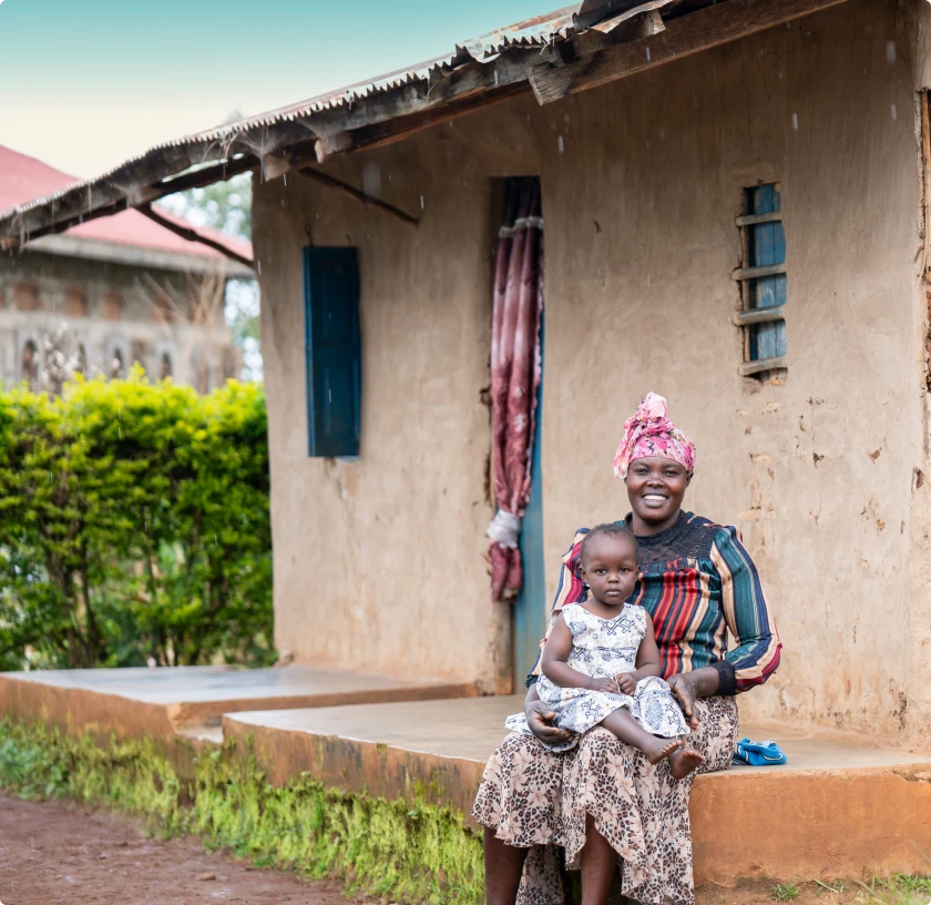 Smiling person holding fresh green leafy vegetables in a garden under a clear sky.