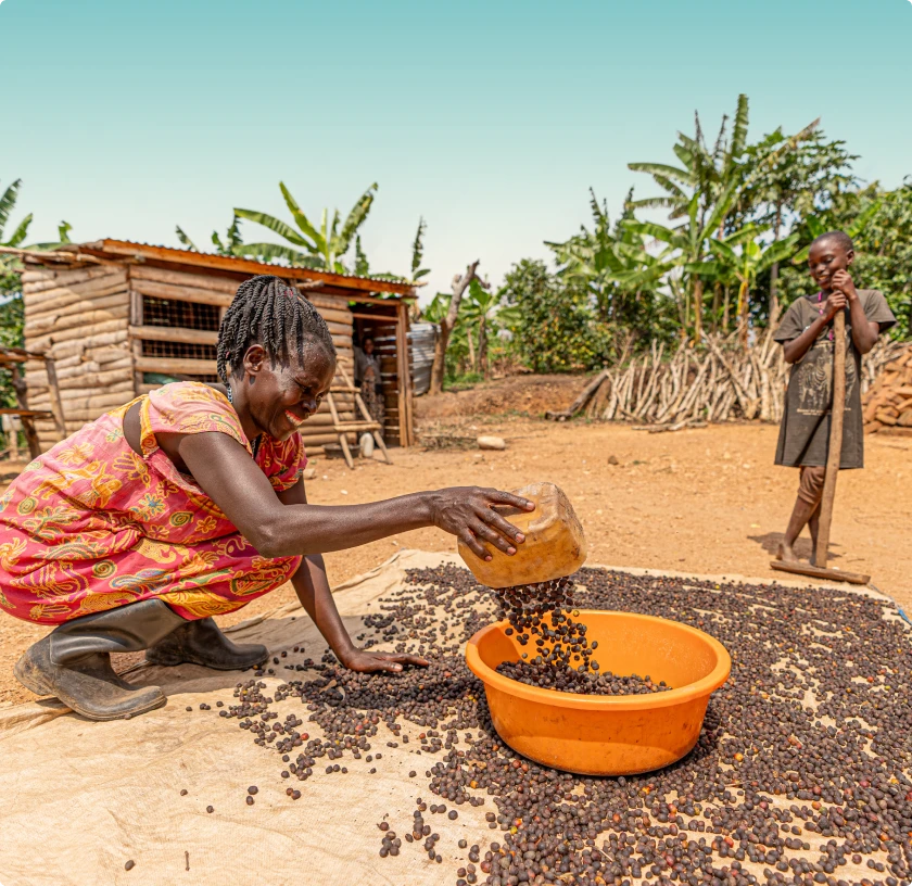 Smiling person in a black shirt holding fresh green leafy vegetables outdoors.