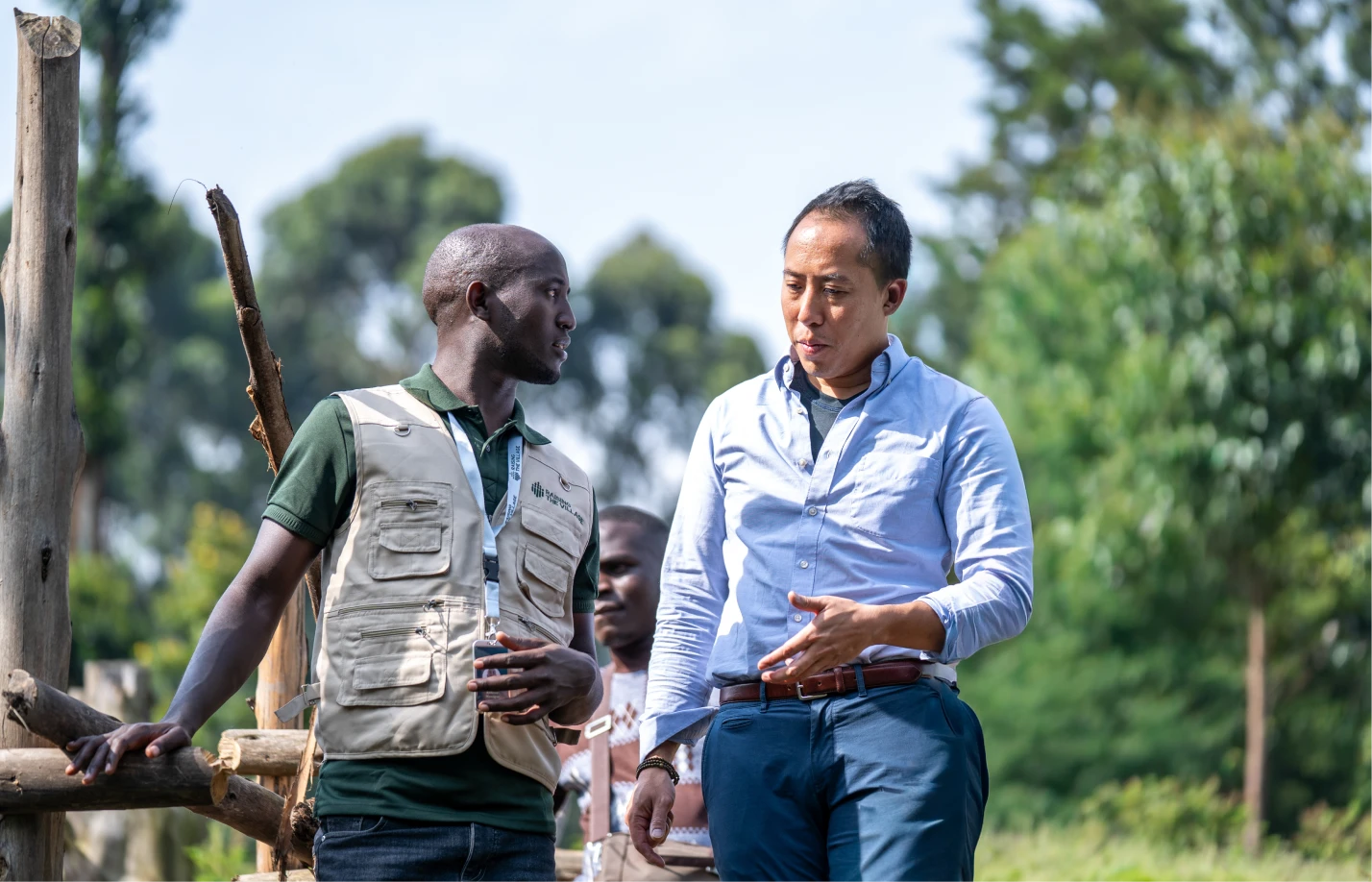 Group of people wearing face masks conversing in a small garden with leafy green plants and soil-filled sacks.