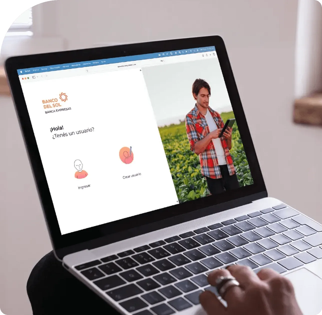 Pantalla de laptop mostrando la página de inicio de sesión del Banco del Sol con opciones para ingresar o crear usuario y una imagen de un hombre en un campo usando una tablet.