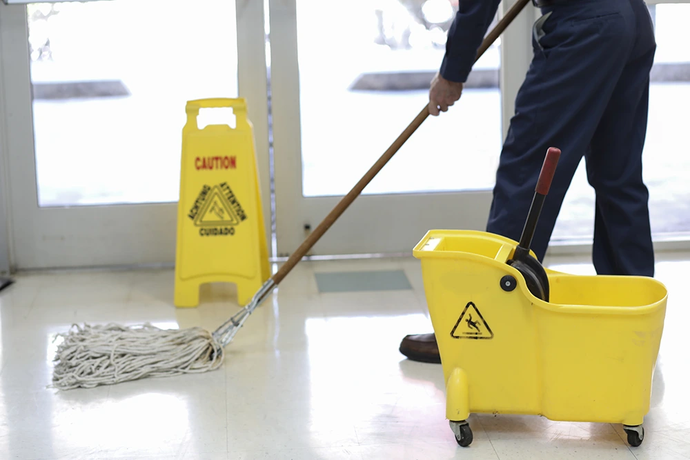 janitor mopping floor with mop and bucket