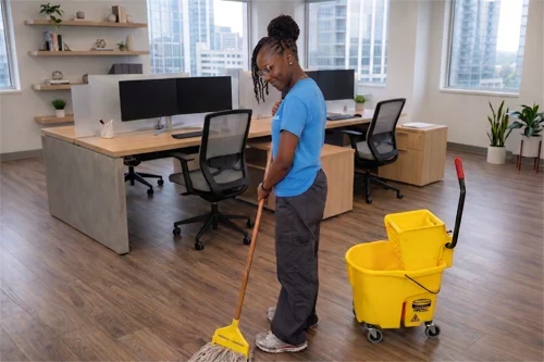 cleaner cleaning an office desk with spray bottle in hand
