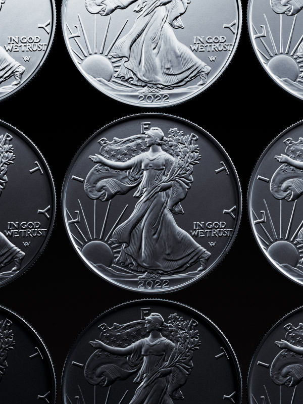 Close-up of multiple 2022 American Silver Eagle coins on a black background, featuring Lady Liberty with a flowing gown and an American flag.