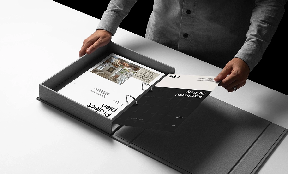 Person organizing printed architectural documents in a sleek binder.