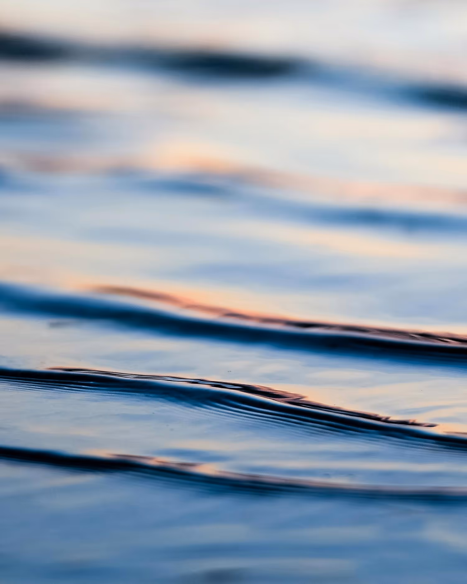 Close-up of gentle water ripples reflecting soft light.