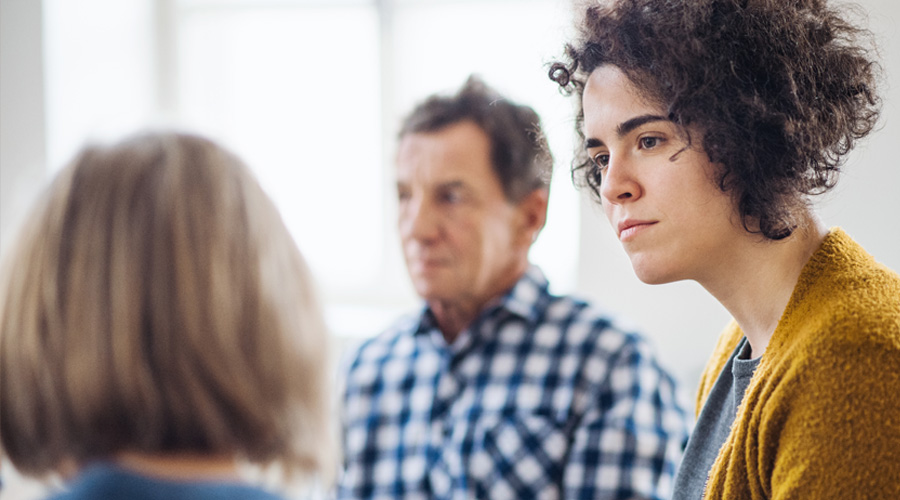 Two adults attentively listening to a person in a group counselling sessions