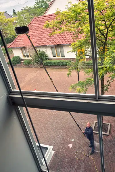 Glasbewassing met telescoopsteel: een glazenwasser van Asito reinigt veilig en efficiënt hoge ramen van buitenaf. Zo blijft ieder gebouw representatief en schoon.