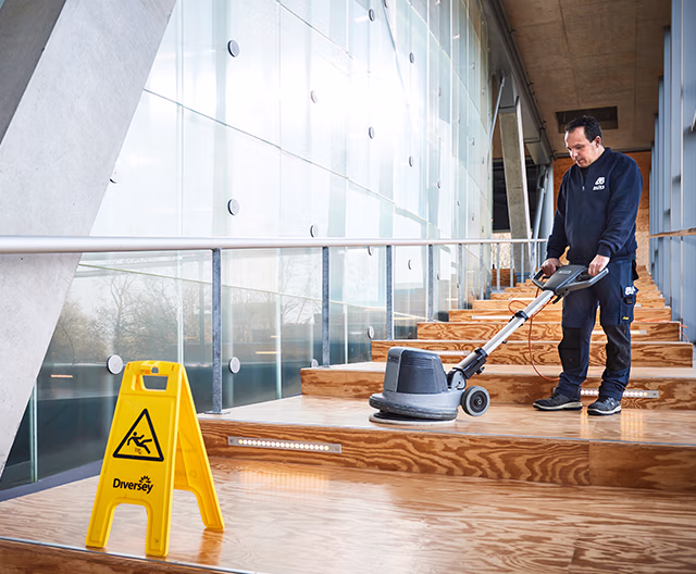 Schoonmaker voert dieptereiniging uit op houten trap