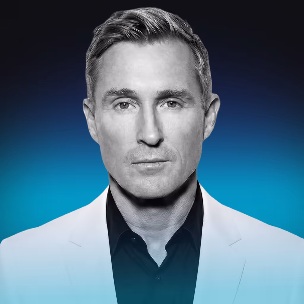 Portrait of a serious man with short gray hair wearing a white blazer and black shirt against a blue gradient background.