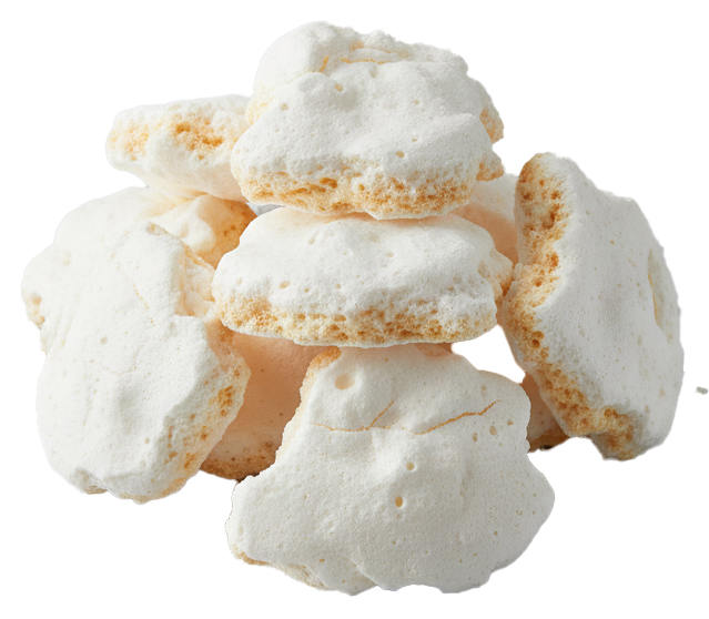 Pile of white meringue cookies with a slightly browned underside on a light surface.