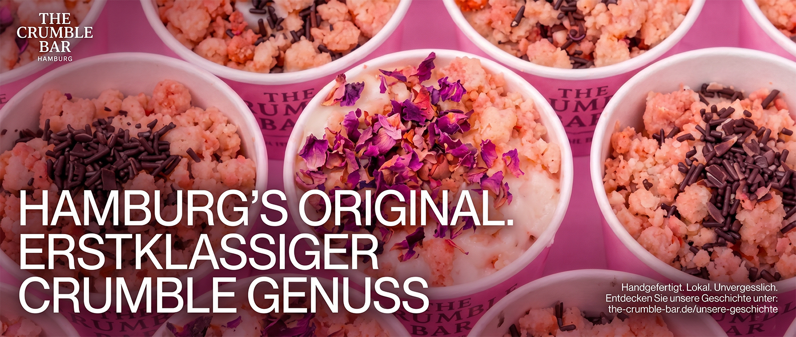 Multiple cups of crumble desserts topped with chocolate sprinkles and rose petals on a pink background.