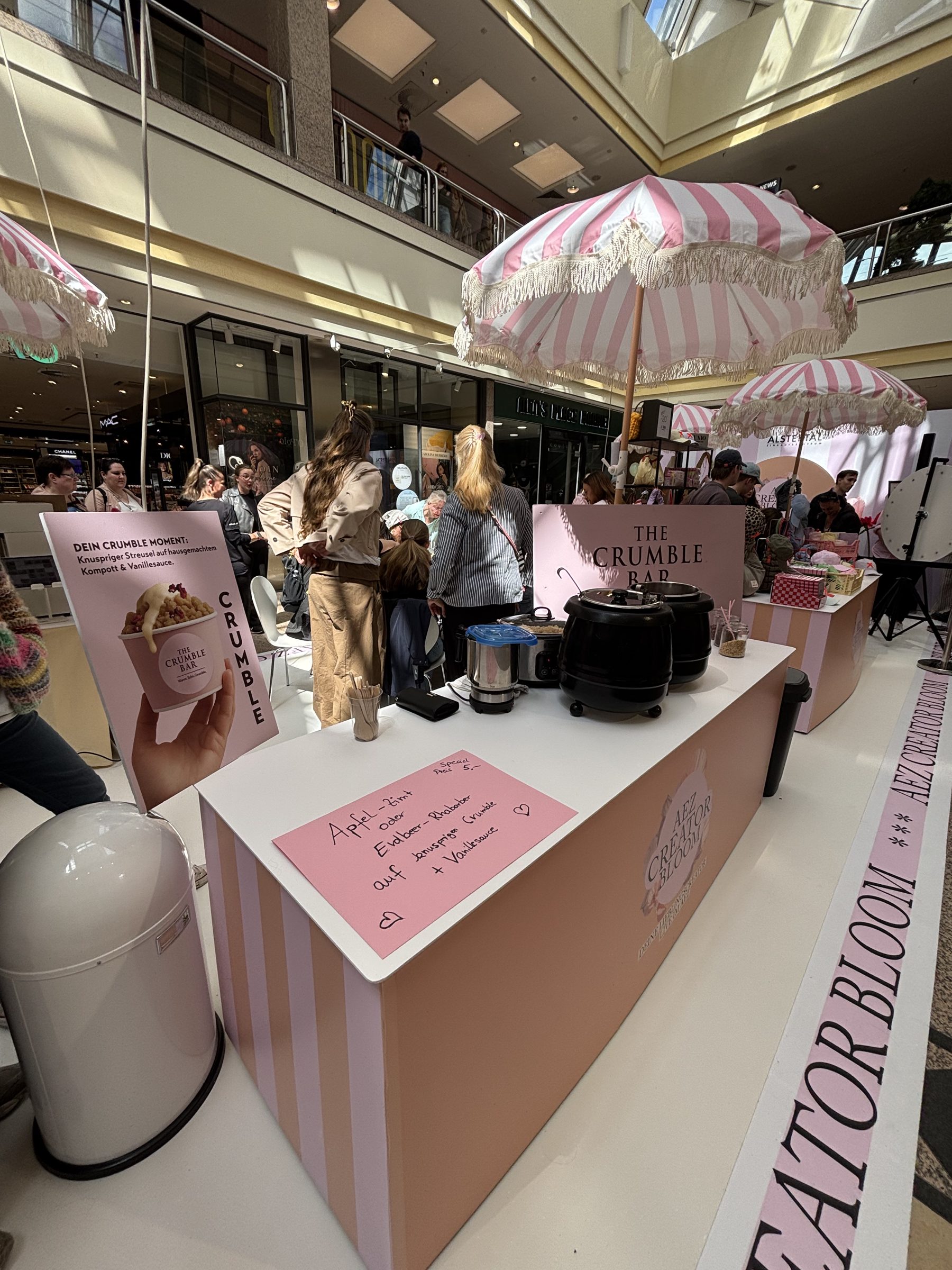 Catering-Stand der Crumble Bar mit rosa Sonnenschirmen bei einem Event in Hamburg