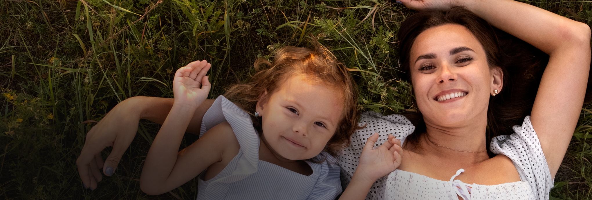 Mother and daughter laying on grass