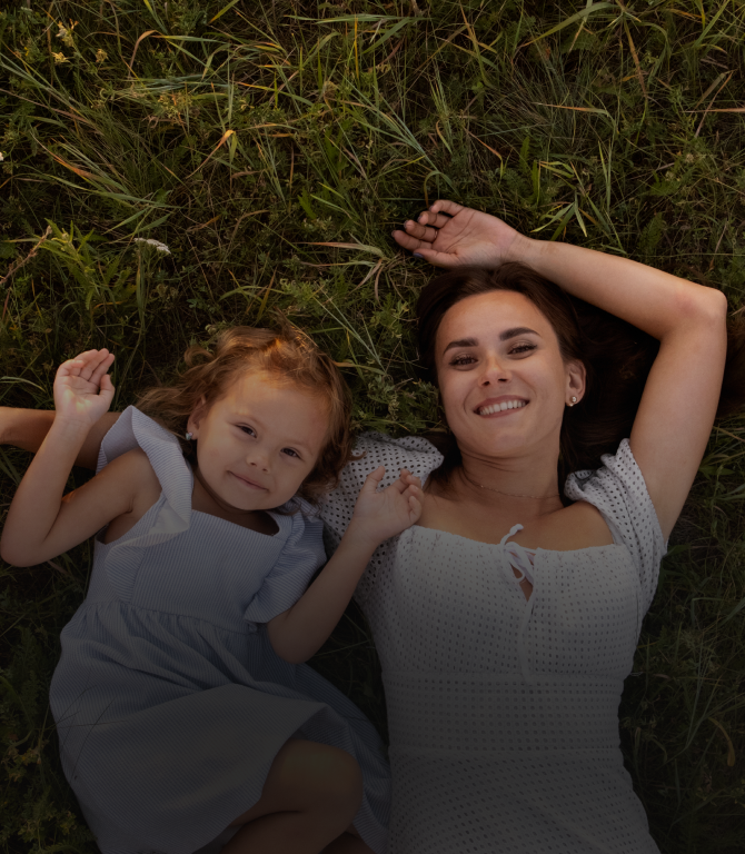 Mother and daughter laying on grass