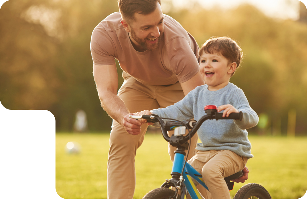 Boy learning how to ride a bicycle accompanied by his fater