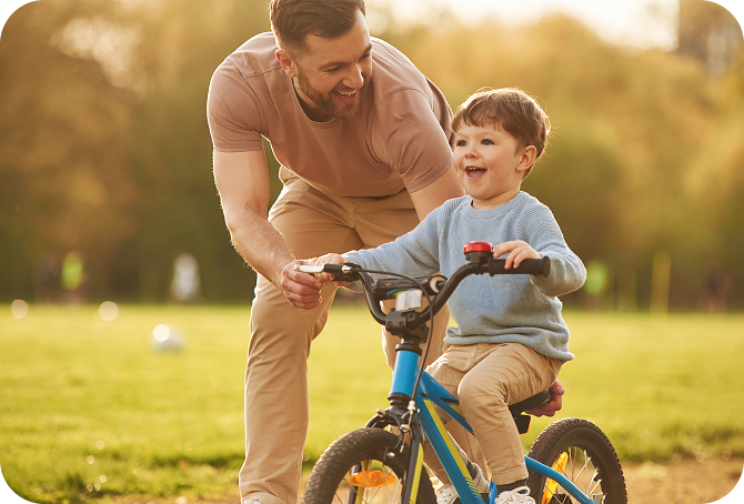 Boy learning how to ride a bicycle accompanied by his fater