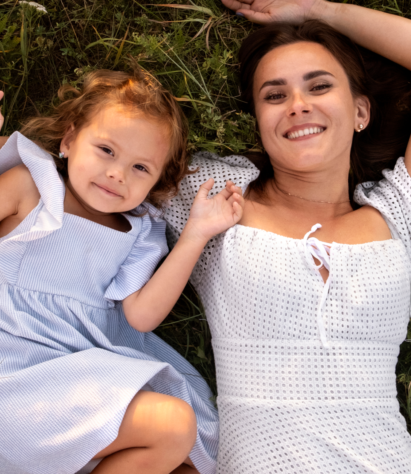 Mother and daughter laying on grass