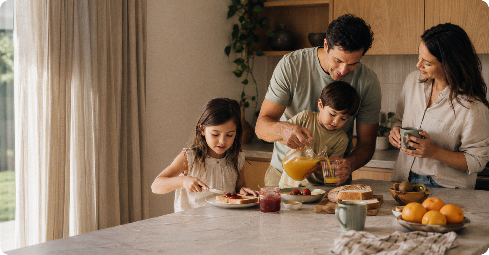 A family making breakfast together in the kitchen, a father pouring juice for his son