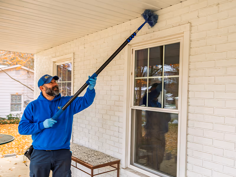 ohio pest control tech sweeping webs from a home
